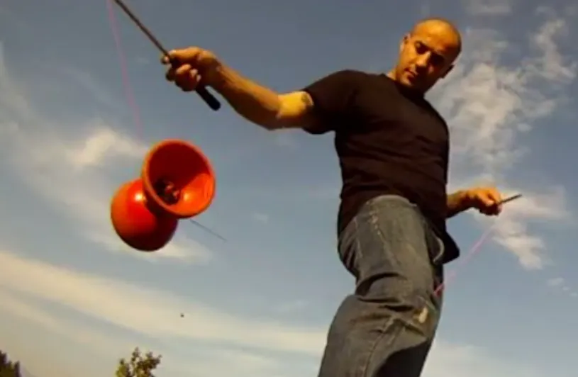 man playing with a red diabolo toy
